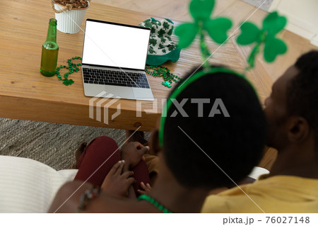 African american couple on st patrick's day video call using laptop with copy space on screen 76027148