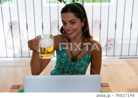 Caucasian woman celebrating st patrick's day making video call wearing deely boppers holding beer Caucasian woman celebrating st patrick's day making video call wearing deely boppers holding beer 76027149
