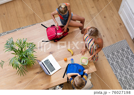 High angle view of caucasian mother with son and daughter preparing packed lunches in kitchen High angle view of caucasian mother with son and daughter preparing packed lunches in kitchen 76027198