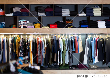 Interior of male clothing store with clothes on hangers and shelves Interior of male clothing store with clothes on hangers and shelves 76030032