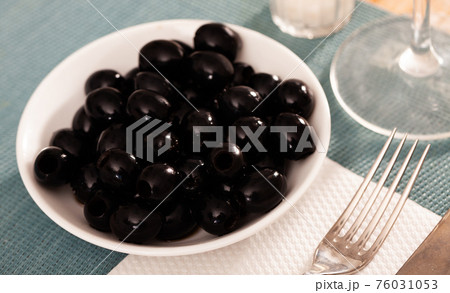 Pickled black olives in white bowl 76031053