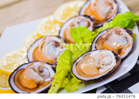 Image of salad of raw dog cockle with lemon and fresh greens 76031476