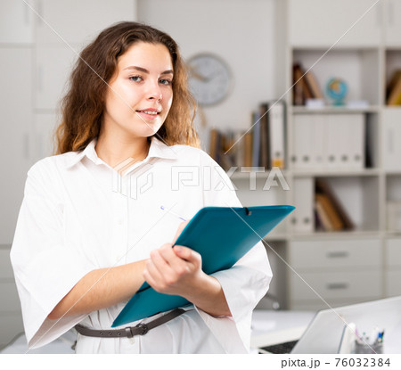 Portrait of smiling young woman holding folder 76032384