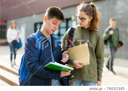 Two students discuss past lessons at college on the street 76032385