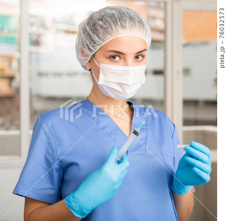 Female nurse or doctor wearing in face mask and medical uniform Female nurse or doctor wearing in face mask and medical uniform 76032573