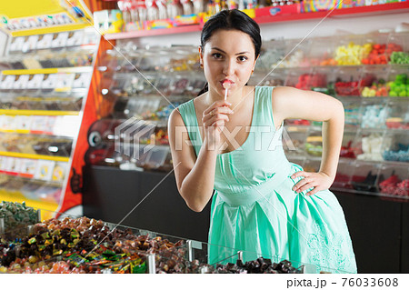 Smiling girl suck candy at sweets store 76033608