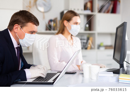 Manager in medical mask working with female colleague in office 76033615