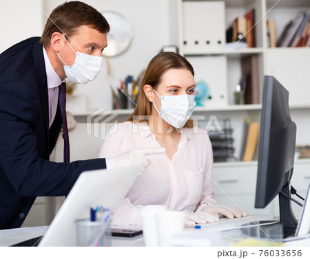 Businessman in face mask working with female assistant in office 76033656