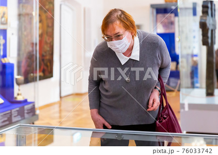 Elderly woman considering exposition in religious museum Elderly woman considering exposition in religious museum 76033742