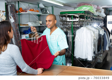 Man dry-cleaning worker giving clothes to customer Man dry-cleaning worker giving clothes to customer 76033849