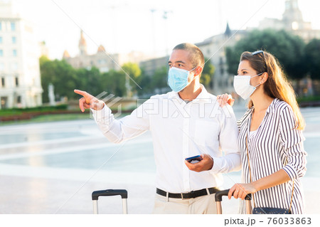 Tourist couple in medical masks visiting city attractions Tourist couple in medical masks visiting city attractions 76033863