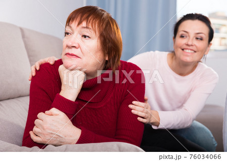 Woman looking away after conflict, daughter tries reconcile 76034066