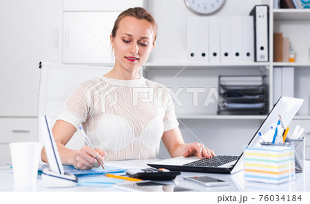 Girl in the office sitting at the table Girl in the office sitting at the table 76034184