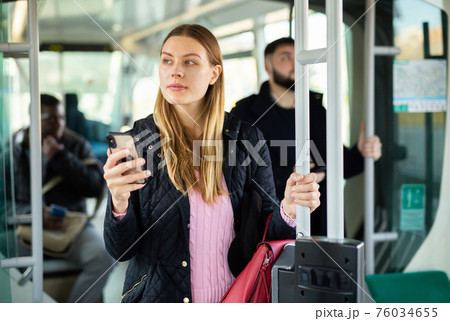 Woman using phone in city bus 76034655