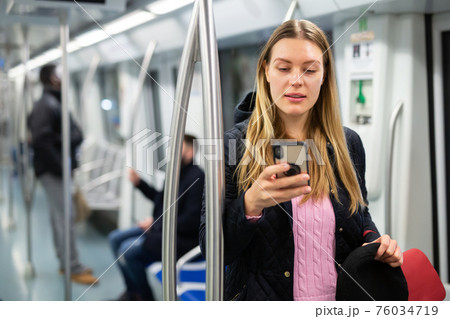 Young woman browsing on phone in metro car Young woman browsing on phone in metro car 76034719
