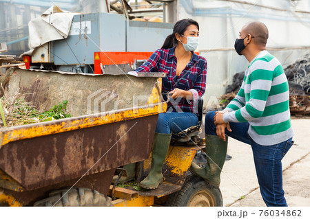 Farm workers in protective masks conduct a dialogue Farm workers in protective masks conduct a dialogue 76034862