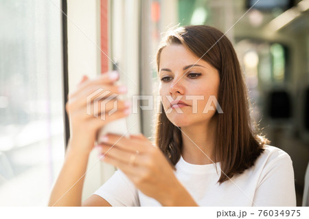Girl using smartphone in public transport Girl using smartphone in public transport 76034975