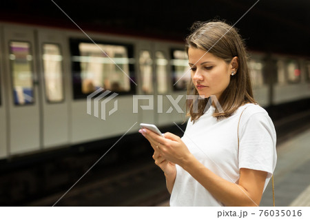 Woman waiting subway car using phone Woman waiting subway car using phone 76035016