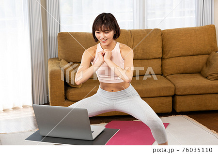 PCの前でスクワットをする女性 PCの前でスクワットをする女性 76035110