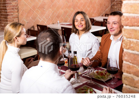 Friends enjoying delicious meal in country restaurant 76035248