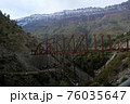 Two people at a height are engaged in the construction of a new bridge in the Himalayan Mountains in the early overcast morning. Dangerous work. 76035647