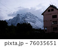 Early cloudy morning in the Himalayan Mountains. Snowy peaks and a pink multi-storey building. 76035651