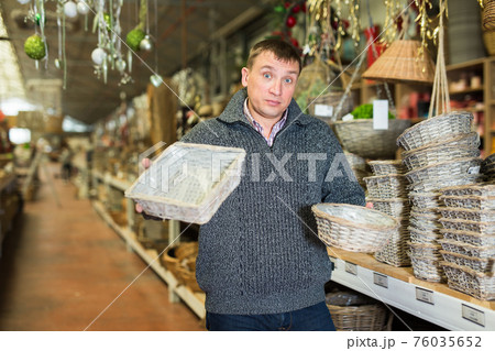 Puzzled man choosing wickerwork in shop 76035652