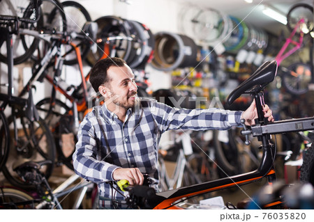 Man adjusts the height of the seat on bike Man adjusts the height of the seat on bike 76035820