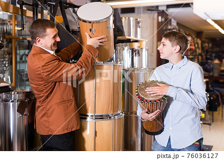 Father and teenage son examining drum units in guitar shop Father and teenage son examining drum units in guitar shop 76036127