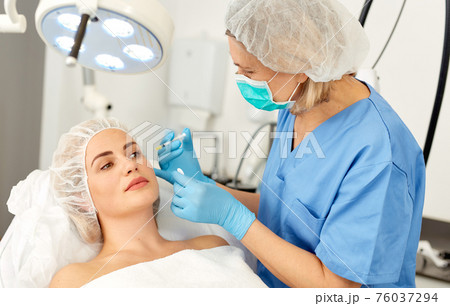 Portrait of woman during beauty facial injections in medical esthetic office 76037294