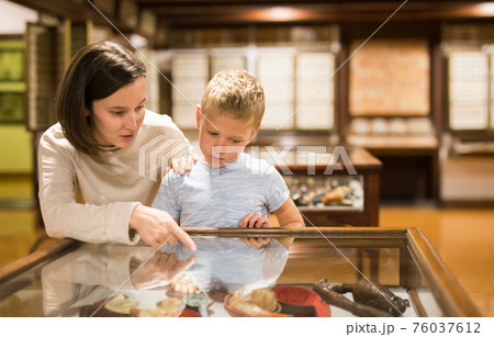 Woman and boy exploring artworks in museum 76037612
