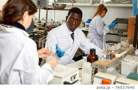 Focused lab technicians man writing report of chemical experiments 76037640