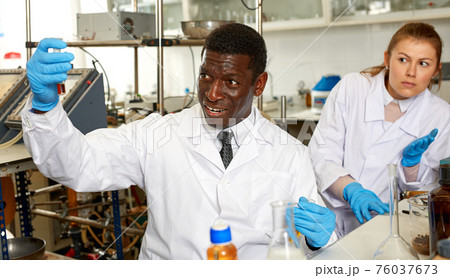Male scientist with test tubes checking for result of chemical experiment Male scientist with test tubes checking for result of chemical experiment 76037673