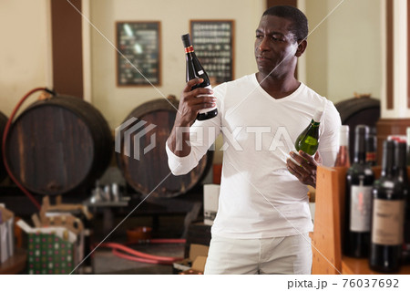 Afro man choosing bottle of wine 76037692