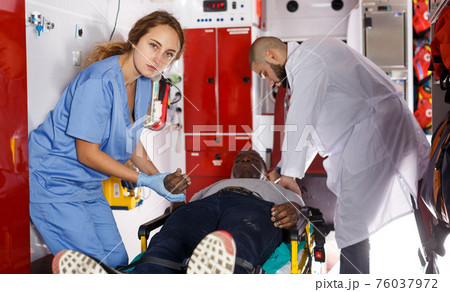 Paramedic team providing first aid to man Paramedic team providing first aid to man 76037972