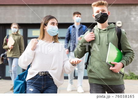 Teenagers in masks walking after lessons Teenagers in masks walking after lessons 76038165