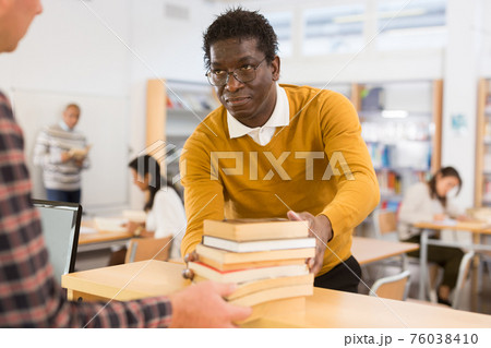 Young adult man returning books at library Young adult man returning books at library 76038410