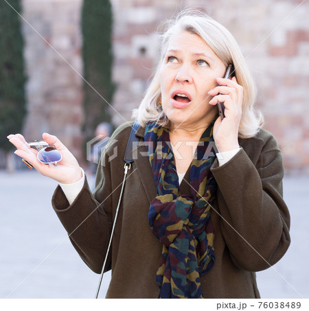 Angry woman is talking by phone on the street Angry woman is talking by phone on the street 76038489