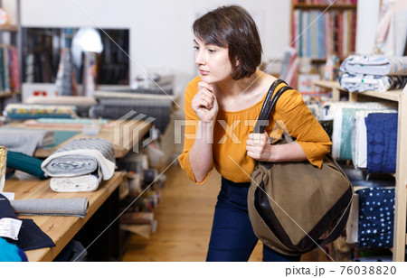 Brunette contemplating about buying in fabric store Brunette contemplating about buying in fabric store 76038820