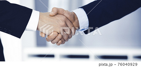Business people shaking hands after contract signing while standing in a modern office. Teamwork and handshake concept 76040929
