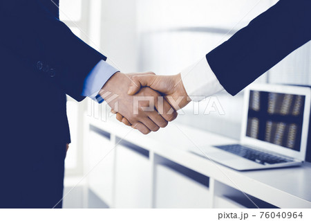 Businessman and woman shaking hands in office. Concept of handshake as success symbol in business Businessman and woman shaking hands in office. Concept of handshake as success symbol in business 76040964