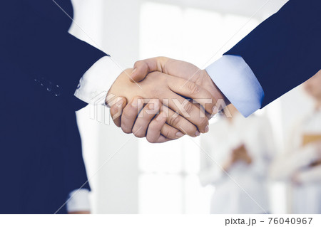 Businessman and woman shaking hands in office. Concept of handshake as success symbol in business 76040967