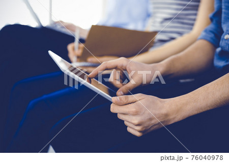 Group of casual dressed business people working at meeting or conference, close-up of hands. Businessman using tablet computer. Teamwork or coaching concept Group of casual dressed business people working at meeting or conference, close-up of hands. Businessman using tablet computer. Teamwork or coaching concept 76040978
