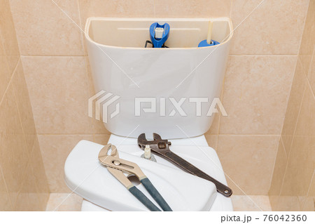 Plumbing tools in the toilet on a white toilet bowl 76042360