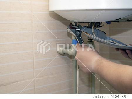 The boiler repair technician uses an adjustable wrench to unscrew or tighten the nut on the pipe. Installing a water heater or dismantling a damaged boiler for later repair. The boiler repair technician uses an adjustable wrench to unscrew or tighten the nut on the pipe. Installing a water heater or dismantling a damaged boiler for later repair. 76042392