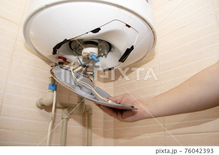 The boiler repair technician uses an adjustable wrench to unscrew or tighten the nut on the pipe. Installing a water heater or dismantling a damaged boiler for later repair. The boiler repair technician uses an adjustable wrench to unscrew or tighten the nut on the pipe. Installing a water heater or dismantling a damaged boiler for later repair. 76042393
