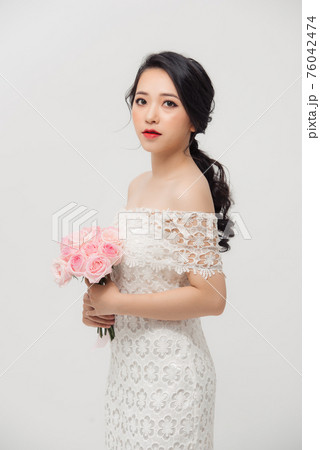 Young beautiful pretty Asian girl standing and holding pink roses over white background. Young beautiful pretty Asian girl standing and holding pink roses over white background. 76042474