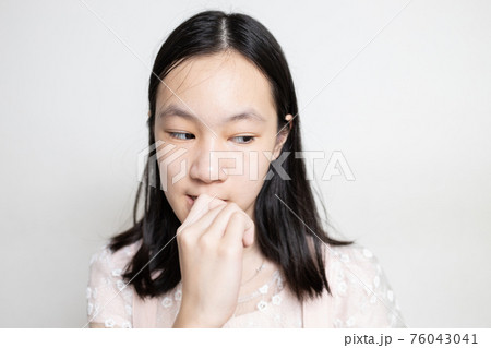 Stressed asian lady girl bites finger nails,thinking about something,anxious problems,scared,anxious with hand on mouth biting her nails,worried student with nervous expression,mental health concept 76043041