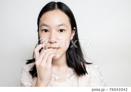 Worried asian teen girl bites fingernails,risk of germs,bacterial disease,Coronavirus into the body from dirty fingers,hand on mouth biting her nails,mental health problems,psychiatric,hygiene concept 76043042