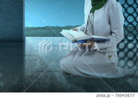 Muslim woman in a veil sitting and reading the Quran Muslim woman in a veil sitting and reading the Quran 76043677